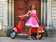 A young woman posing in a dress behind a scooter