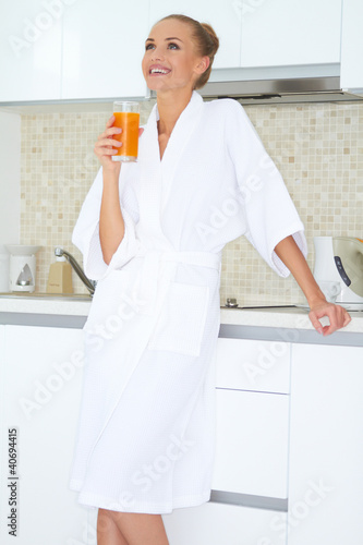 Photo: Woman enjoying fresh orange juice for breakfast Woman enjoying fresh orange juice for breakfast