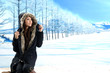 fashion girl portrait with a hooded coat posing in winter park