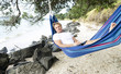 A man happily relaxing in a hammock on the beach. A man happily relaxing in a hammock on the beach.