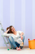 Photo: Young brunette sitting on floor after painting. Young brunette sitting on floor after painting.