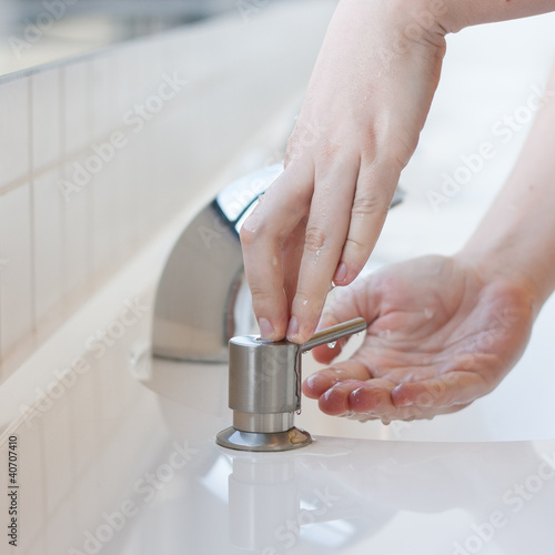Photo: Washing hands in a public restroom - applying soap Washing hands in a public restroom - applying soap