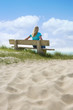 Frau auf einer Bank am Meer