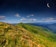 Summer landscape in the mountains with stars and moon in the sky