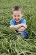 young boy seated in meadow young boy seated in meadow