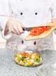chef adds chopped tomatoes in a glass bowl chef adds chopped tomatoes in a glass bowl