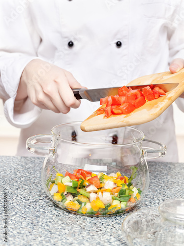 Photo: chef adds chopped tomatoes in a glass bowl chef adds chopped tomatoes in a glass bowl