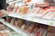 Variety of fresh sausages on shelves in supermarket