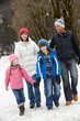 canvas print picture - Family Walking Along Snowy Street In Ski Resort