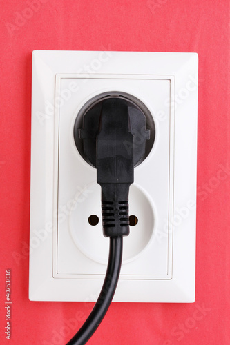 Photo: White electric socket with plug on the wall White electric socket with plug on the wall