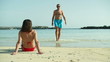 Sexy woman in bikini looking at man walking on the beach