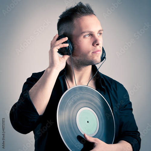 Photo: Young man working as dj with ear-phones and disc. Young man working as dj with ear-phones and disc.