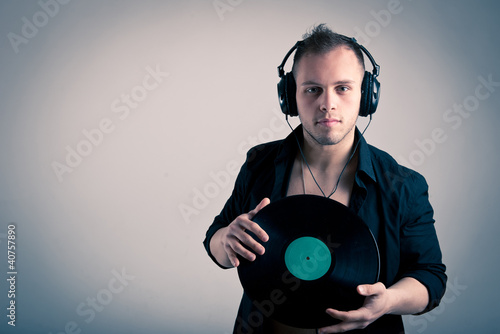 Photo: Young man working as dj with ear-phones and disc. Young man working as dj with ear-phones and disc.