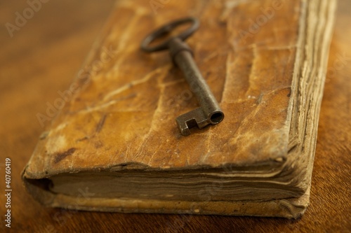 Photo: Old metal key on vintage book. Old metal key on vintage book.