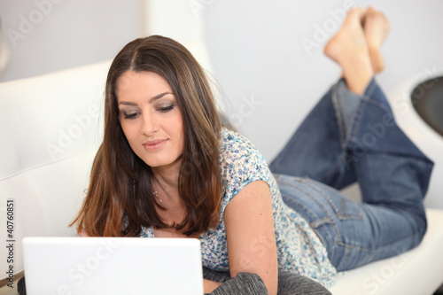 Photo: Woman laying on sofa with laptop Woman laying on sofa with laptop