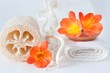 Spugna vegetale con fiori arancioni e asciugamano bianco