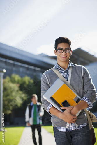 Photo: Student carrying folders outdoors Student carrying folders outdoors
