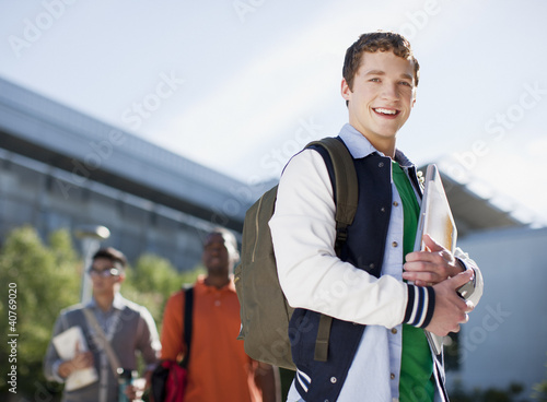 Photo: Student carrying folders outdoors Student carrying folders outdoors