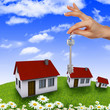 House and human hand against blue sky