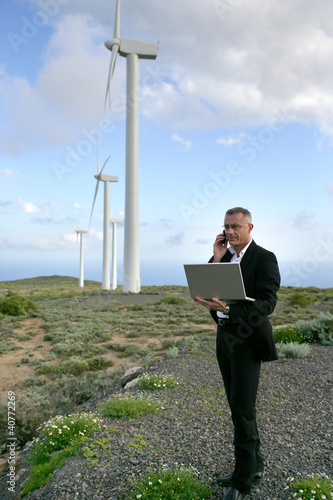 Foto: Businessman using a laptop on a windfarm Businessman using a laptop on a windfarm