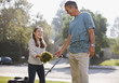 Father and daughter mowing lawn together