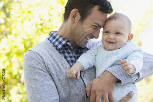 Photo: Smiling father holding baby outdoors Smiling father holding baby outdoors