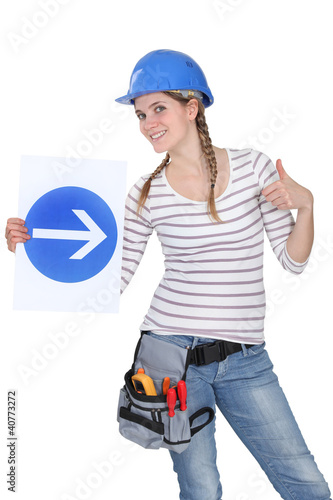 Foto: Smiling woman showing road sign Smiling woman showing road sign