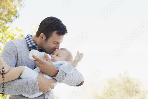 Foto: Father bottle feeding baby outdoors Father bottle feeding baby outdoors