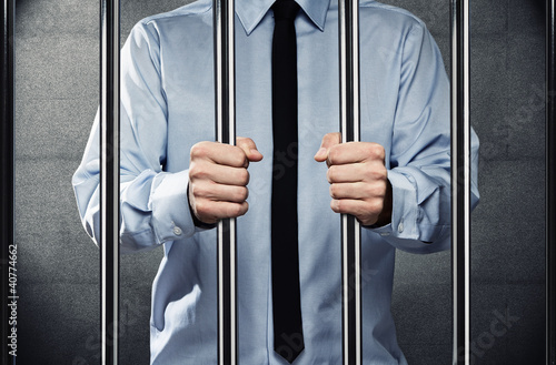 Photo: Young corrupted businessman behind the prison bars Young corrupted businessman behind the prison bars