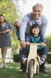Older man pushing grandson in backyard