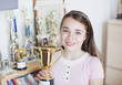 Smiling girl holding trophy in bedroom