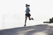 Woman running along lake in park