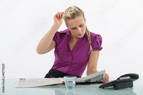 Photo: Blond office worker reading newspaper Blond office worker reading newspaper