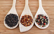 Three types of pepper on wooden spoons