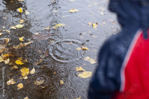 Foto: Girl watching rain drops in puddle Girl watching rain drops in puddle