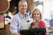 Workers using cash register in supermarket