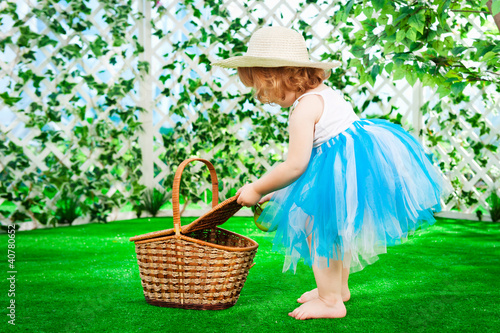 Photo: little girl with a basket on the lawn little girl with a basket on the lawn
