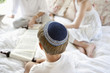 Boy wearing yarmulke and reading Torah scrolls