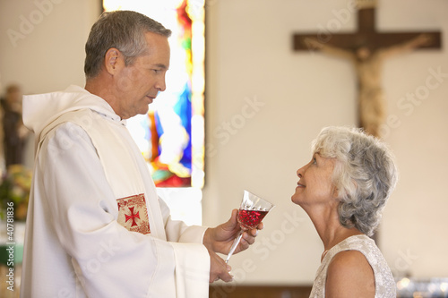 Photo: Priest giving communal wine to woman Priest giving communal wine to woman