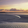 Water carving path through sandy beach