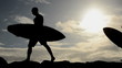 Two Surfers Carrying Their Boards At Sunset In Hawaii