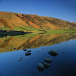 Rolling hills reflected in still lake