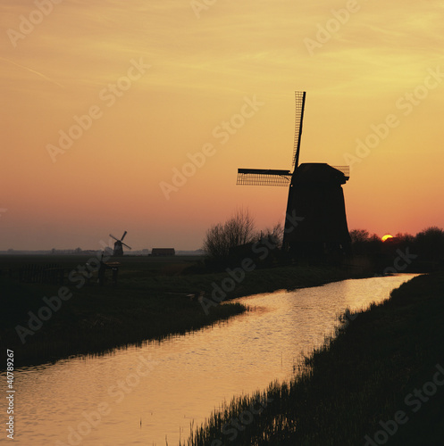 Photo: Silhouette of windmill and river in rural landscape Silhouette of windmill and river in rural landscape