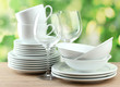 Clean dishes on wooden table on green background