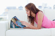 Teenage girl reading a magazine while lying on a sofa