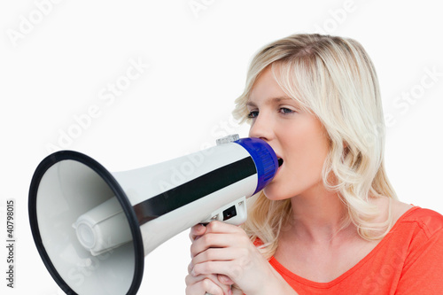 Photo: Young woman looking on the side while speaking into a megaphone Young woman looking on the side while speaking into a megaphone