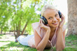 Photo: Smiling woman listening to music while lying on the lawn Smiling woman listening to music while lying on the lawn