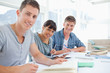 Three students sitting together as they all look into the camera