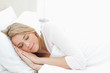 Woman resting in bed, with hands by her head