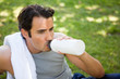 Man with a towel on his shoulder drinking from a sports bottle